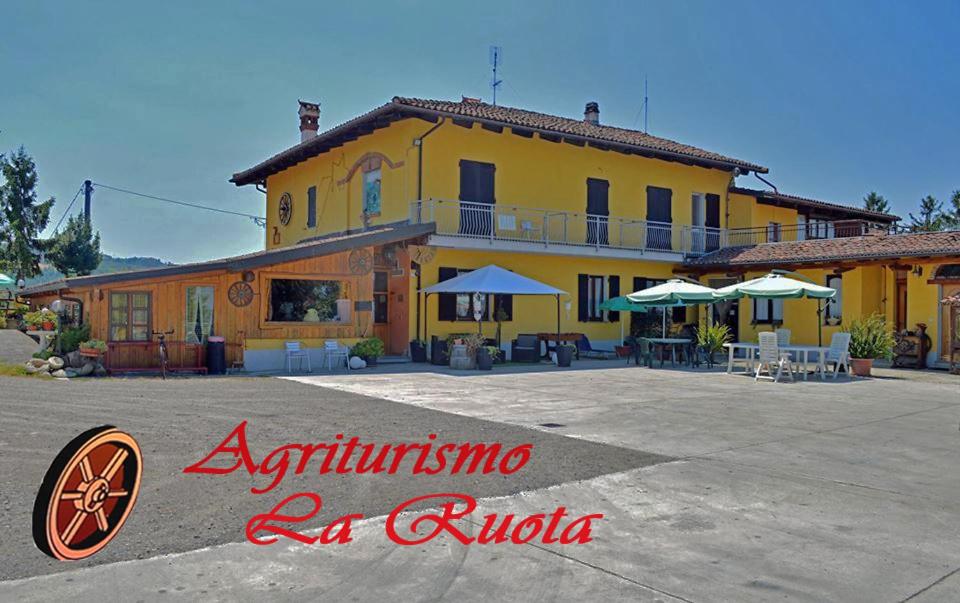 un edificio amarillo con mesas y sombrillas delante en Agriturismo La Ruota, en Montelupo Albese