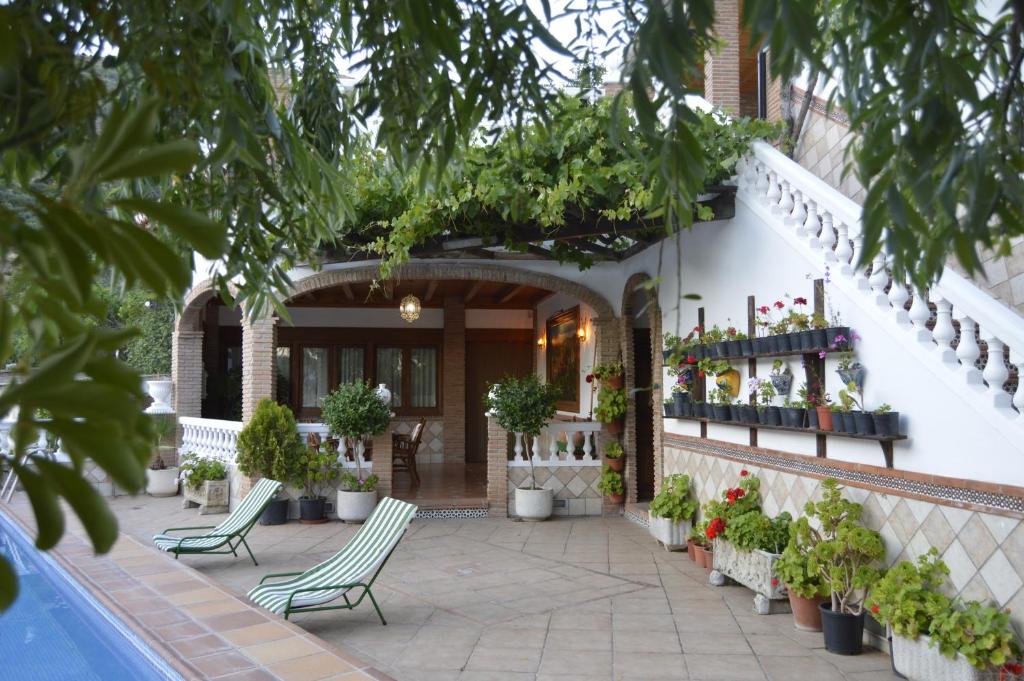 a patio with chairs and potted plants next to a building at Casa Los Barranquillos in Lanjarón