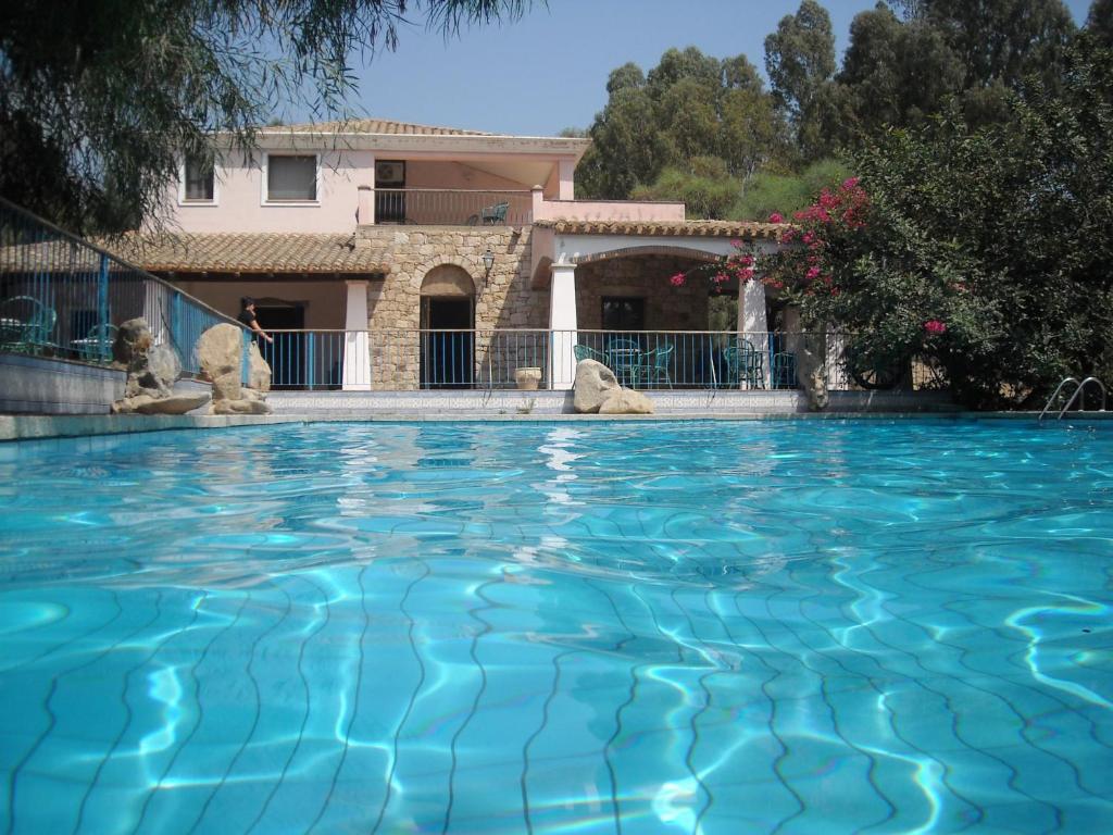 una grande piscina con acqua blu di fronte a una casa di Principessa de Navarra a Santa Maria Navarrese