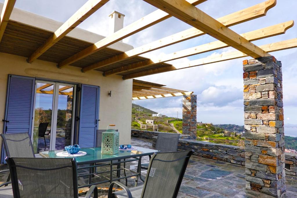 une salle à manger avec une table et des chaises sur une terrasse dans l'établissement Cycladic Villa with sea view!, à Ioulída