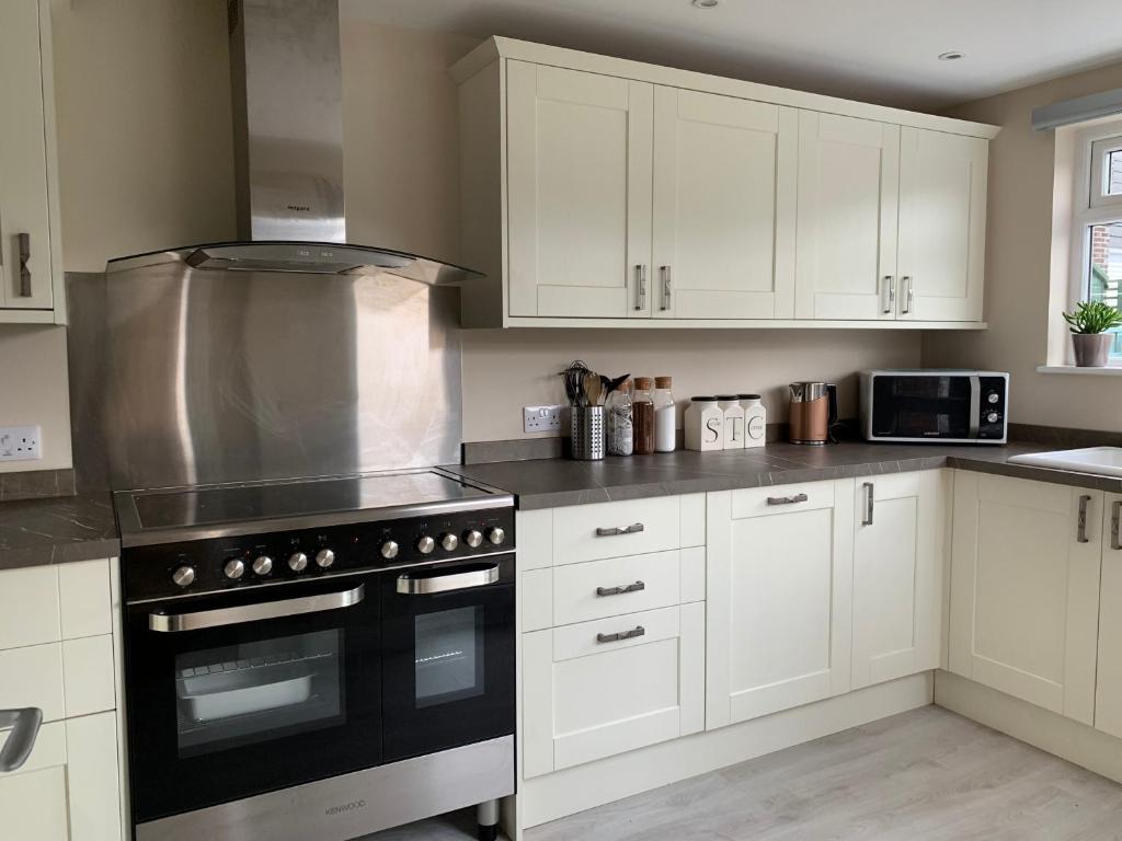 a kitchen with white cabinets and a black stove top oven at Newly Renovated & Spacious House in Seahouses