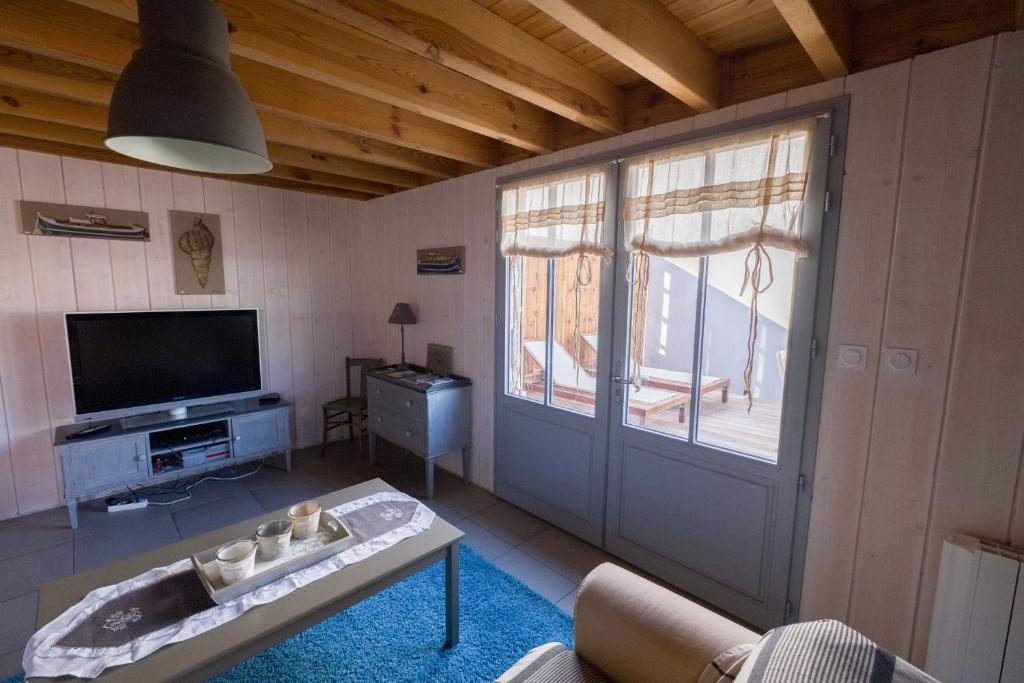 een woonkamer met een deur en een tv bij La cabane 26 D in Andernos-les-Bains