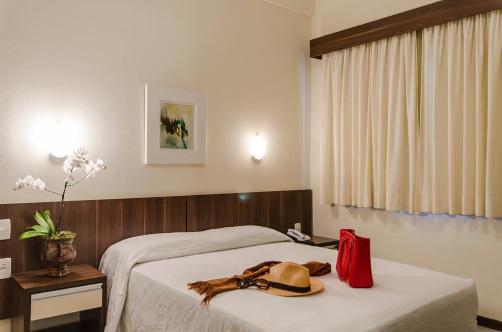 ein Hotelzimmer mit einem Bett mit Hut darauf in der Unterkunft Hotel Ryan in Balneário Camboriú