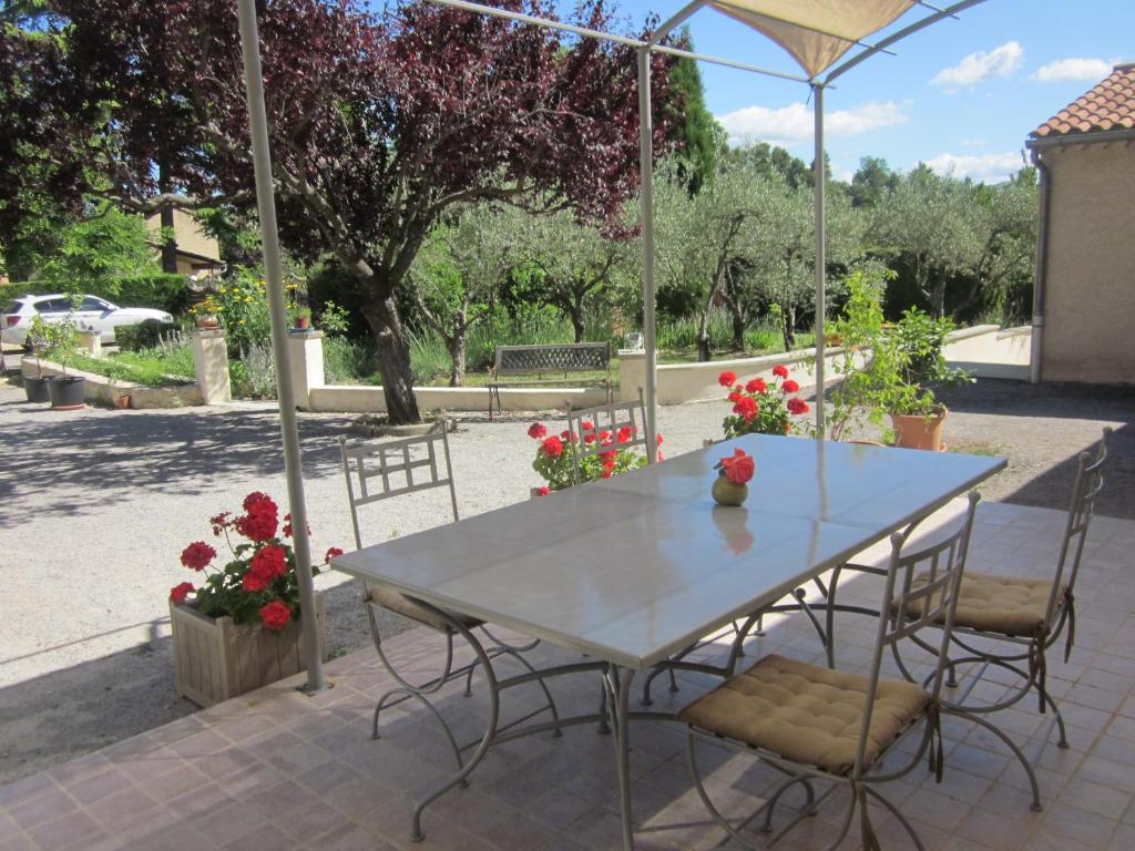 a table and chairs in a patio with flowers at Les Verveines de Vaison in Vaison-la-Romaine