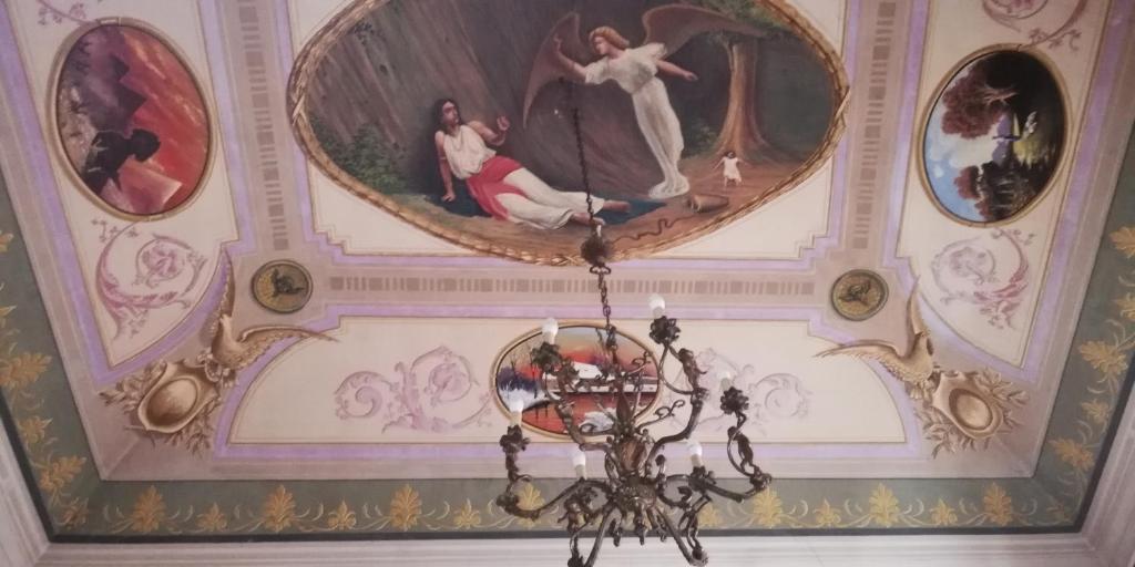 a chandelier hanging from a ceiling with paintings on it at Gatti al Borgo in Catania