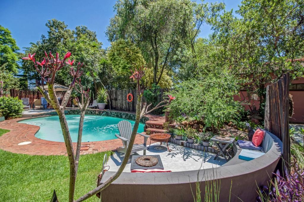 einen Hinterhof mit einem Pool mit einer Bank und Bäumen in der Unterkunft Sitatunga Guest Lodge in Johannesburg