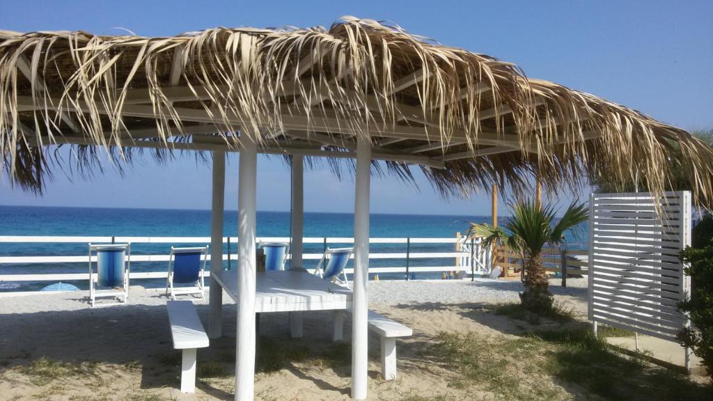 um banco debaixo de um guarda-sol de palha na praia em Villetta sul mare em Capo Vaticano