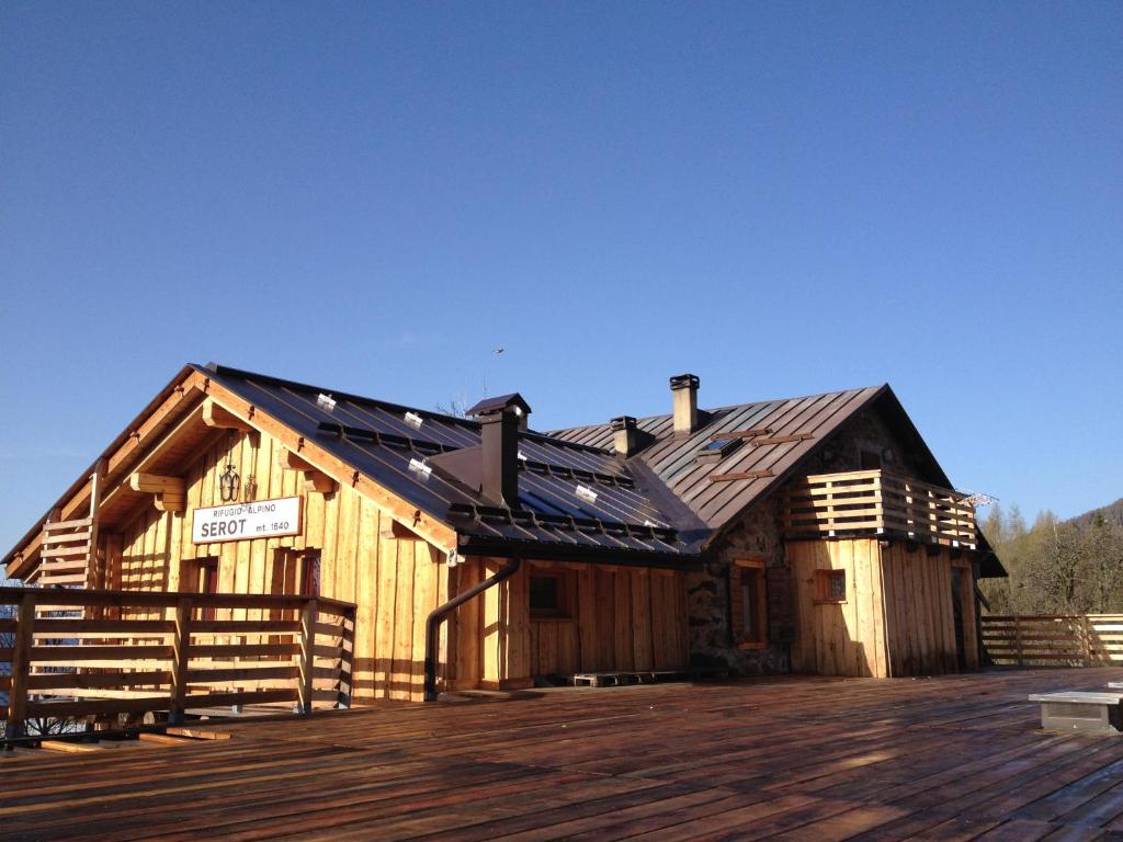 ein großes Holzgebäude mit einem Dach auf einer Terrasse in der Unterkunft Rifugio Serot in Rundscheinberg