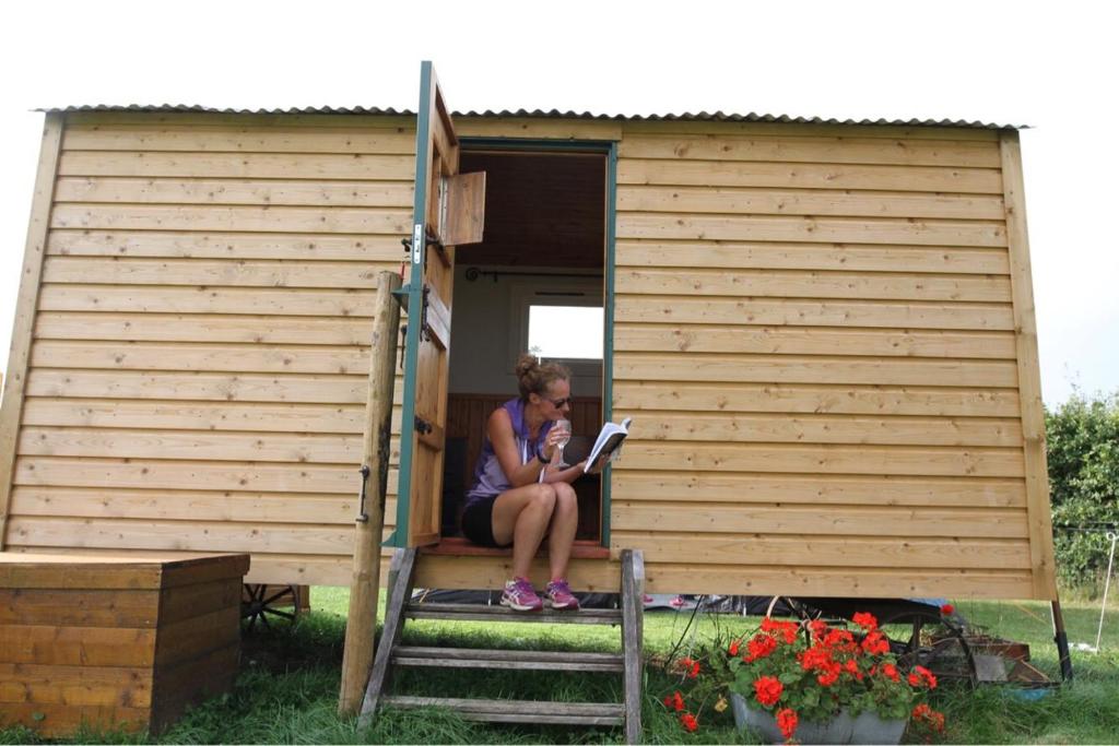 a woman sitting on the porch of a tiny house at Shepherdshuts-southeast in Ashford