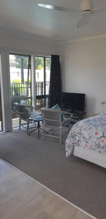 1 dormitorio con cama, sillas y balcón en Kerikeri Central Apartment, en Kerikeri