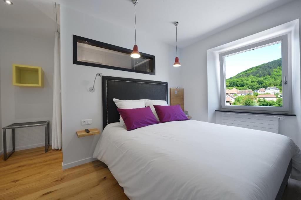 1 dormitorio con 1 cama blanca grande con almohadas moradas en La Bonne Auberge en Clerval