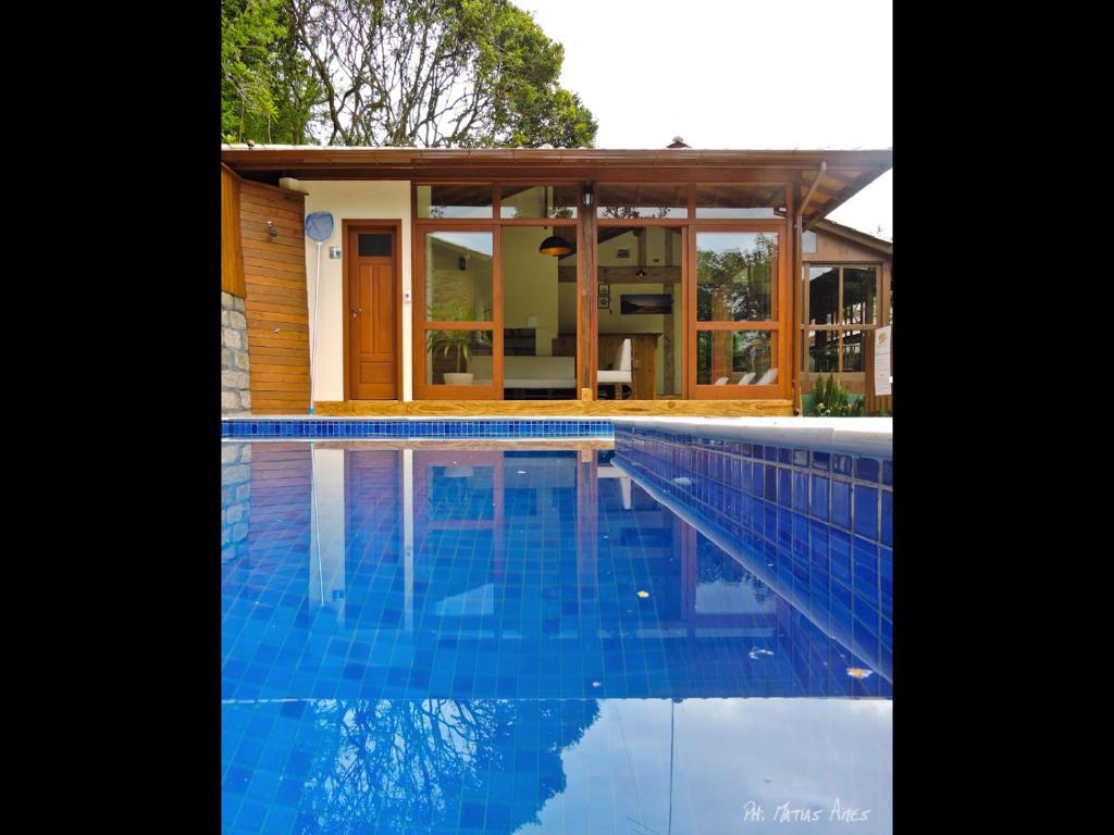 a house with a swimming pool in front of a house at Pousada Morada Flor da Terra in Guarda do Embaú