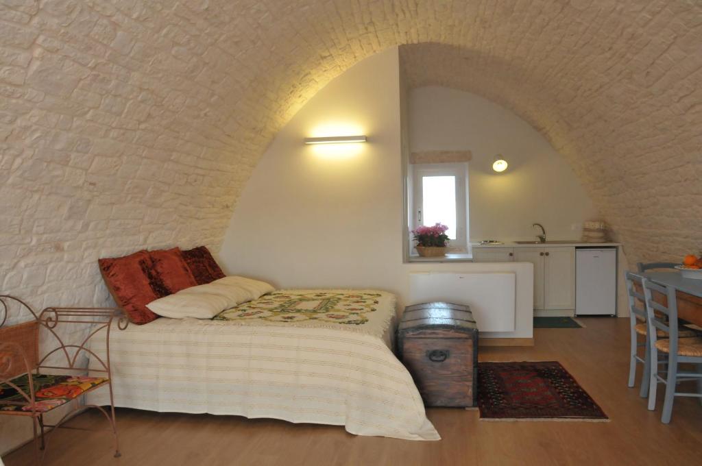 a bedroom with a bed and a table and a kitchen at Palazzo Agrusti - Residenza D'Epoca in Alberobello