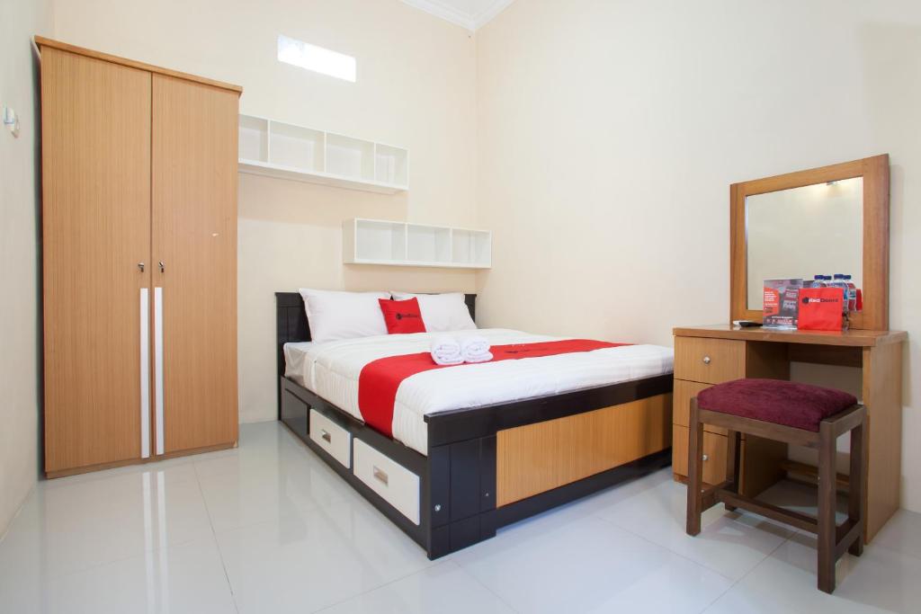 a bedroom with a bed and a dresser and a mirror at RedDoorz Syariah near UNTAG Banyuwangi in Banyuwangi