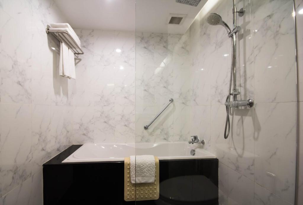 a white bathroom with a shower and a sink at Sima Thani Hotel in Nakhon Ratchasima