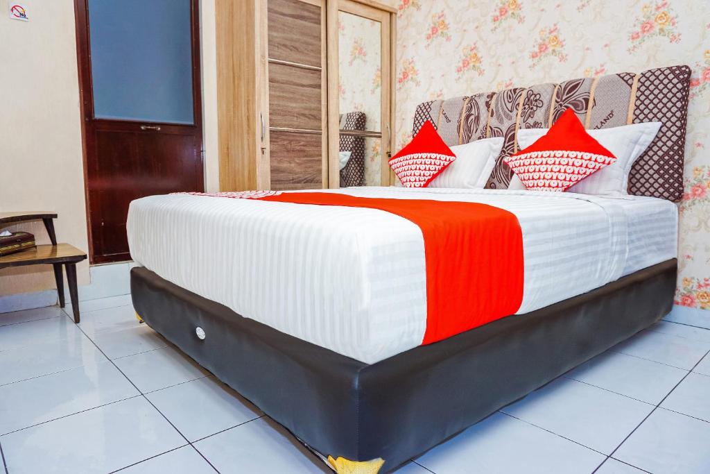 a bedroom with a bed with red and white pillows at OYO 433 Nelvi Guest House Syariah in Padang