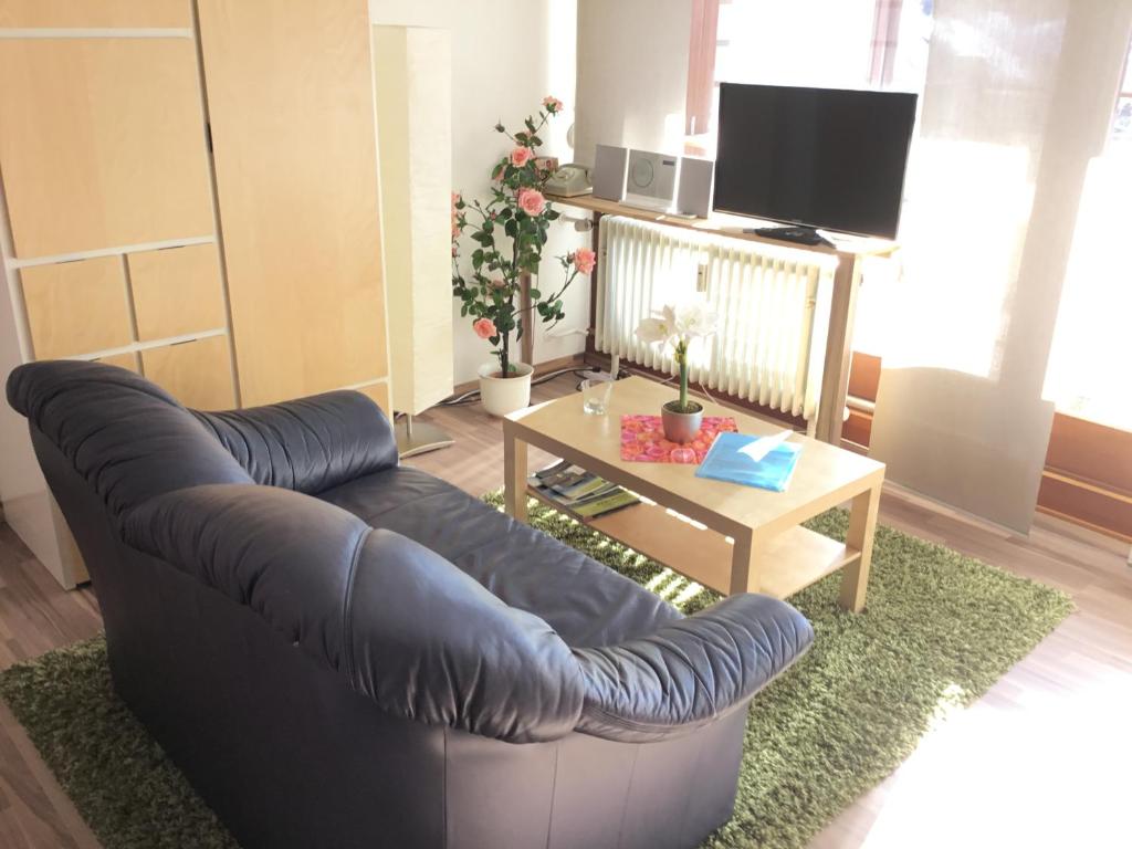 a living room with a blue leather couch and a table at 1Z. FeWo 231 barbo Schwimmbad-Sauna-Fitness in Schönwald