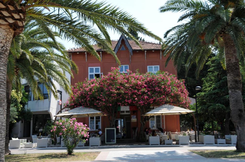 a red building with palm trees and pink flowers at Le Petit Chateau in Bar
