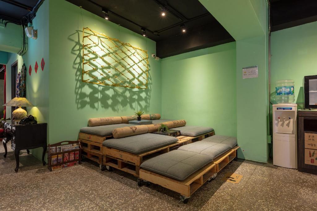 a room with four beds on a green wall at Cho Hotel in Taipei