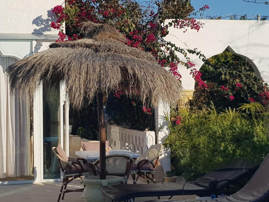a patio with a table and chairs and flowers at Menzel Churasco Djerba in Aghīr