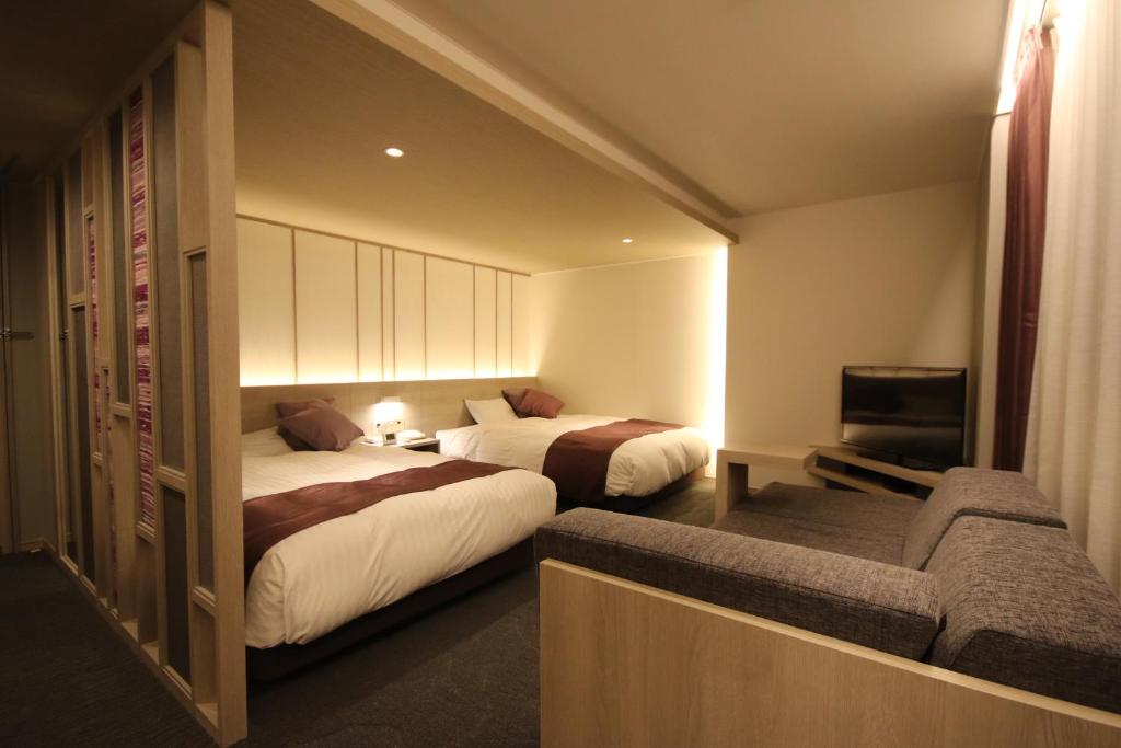 una habitación de hotel con dos camas y un sofá en Kita Hotel, en Morioka