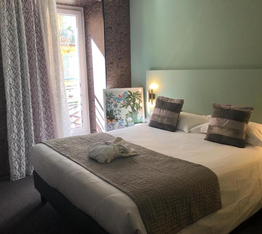 a dog laying on a bed in a bedroom at Hôtel Le G (ex Le Genève) in Nice