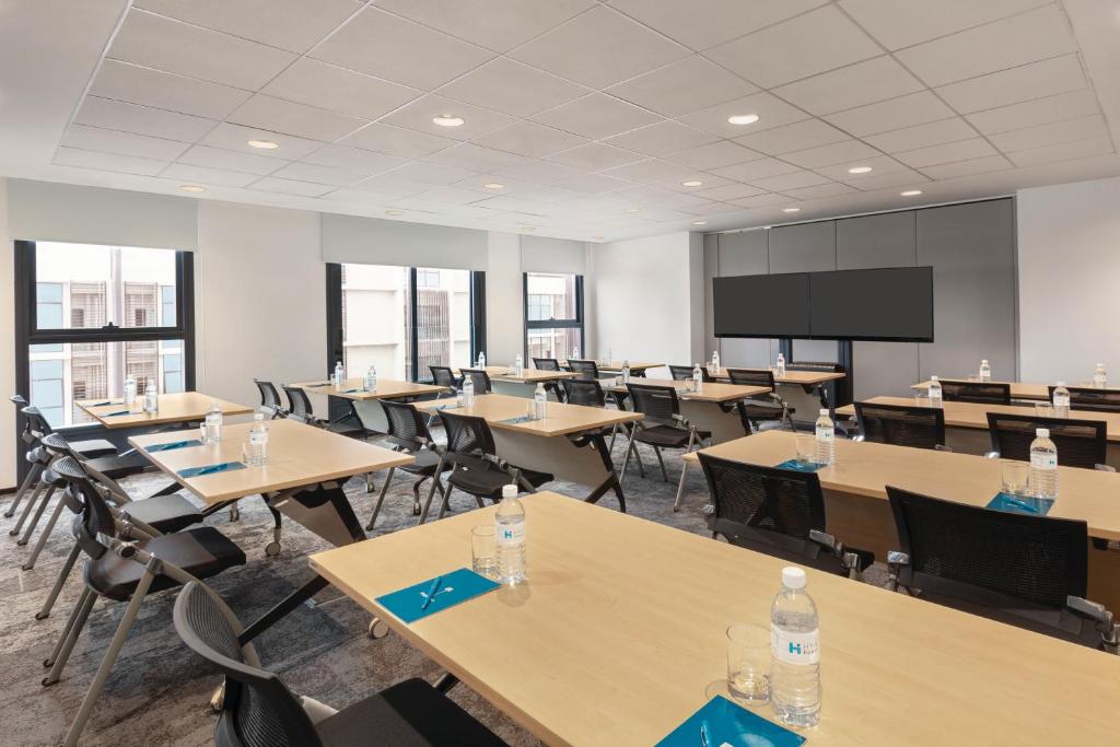 A classroom-style meeting room prepared with tables, water, and screens.