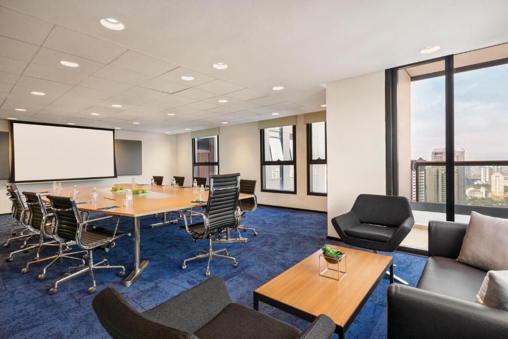 A bright conference room with a presentation screen and city-facing windows.