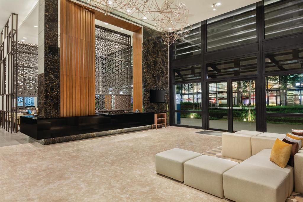 A spacious entrance lounge with white modular seating, a television, and tall glass doors.