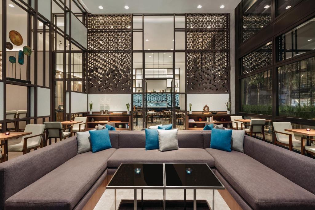 A large communal lounge centered on a sectional sofa, with additional tables and chairs beyond.