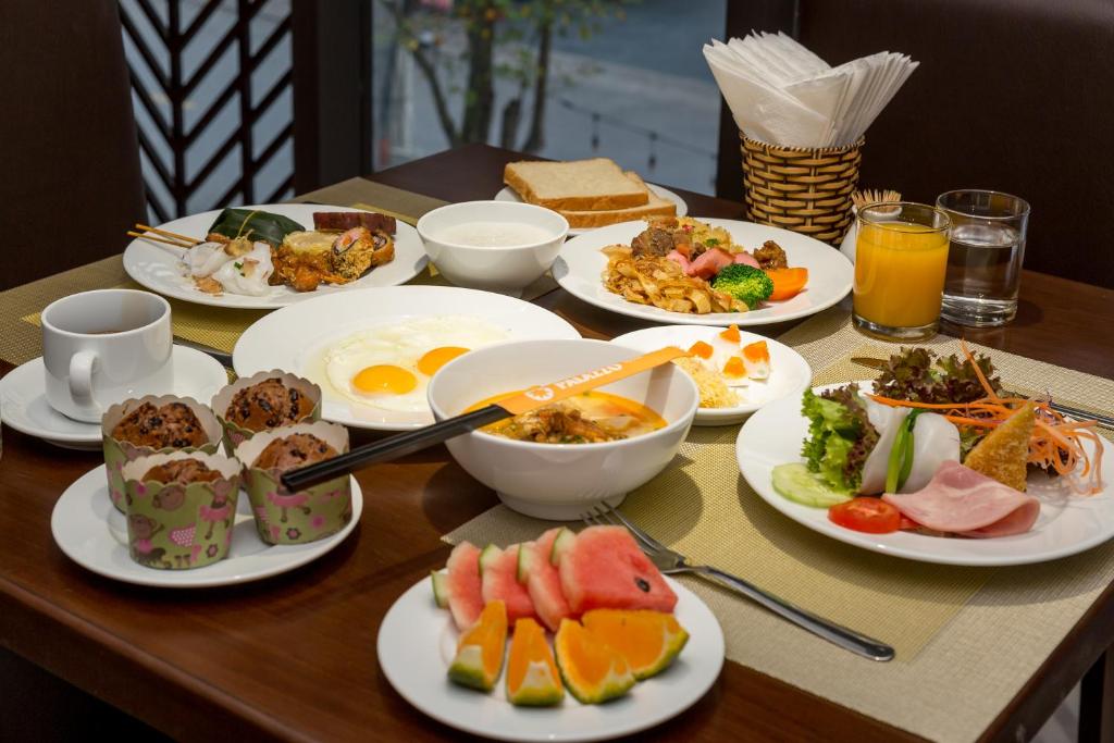 A table is set with a varied breakfast including eggs, soup, fruit, salad, pastries, juice and coffee.