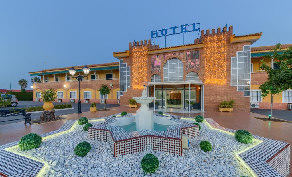 un hôtel avec une fontaine en face d'un bâtiment dans l'établissement Hotel Torre De Los Guzmanes, à La Algaba