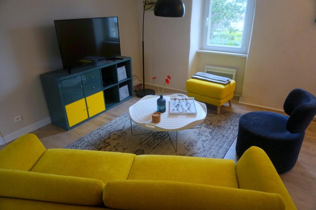 a living room with a yellow couch and a tv at Le Gîte du Port in Roscoff