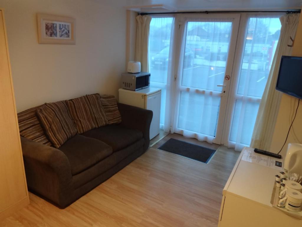 a living room with a couch and sliding glass doors at Travellers Rest Motel in Ingoldmells