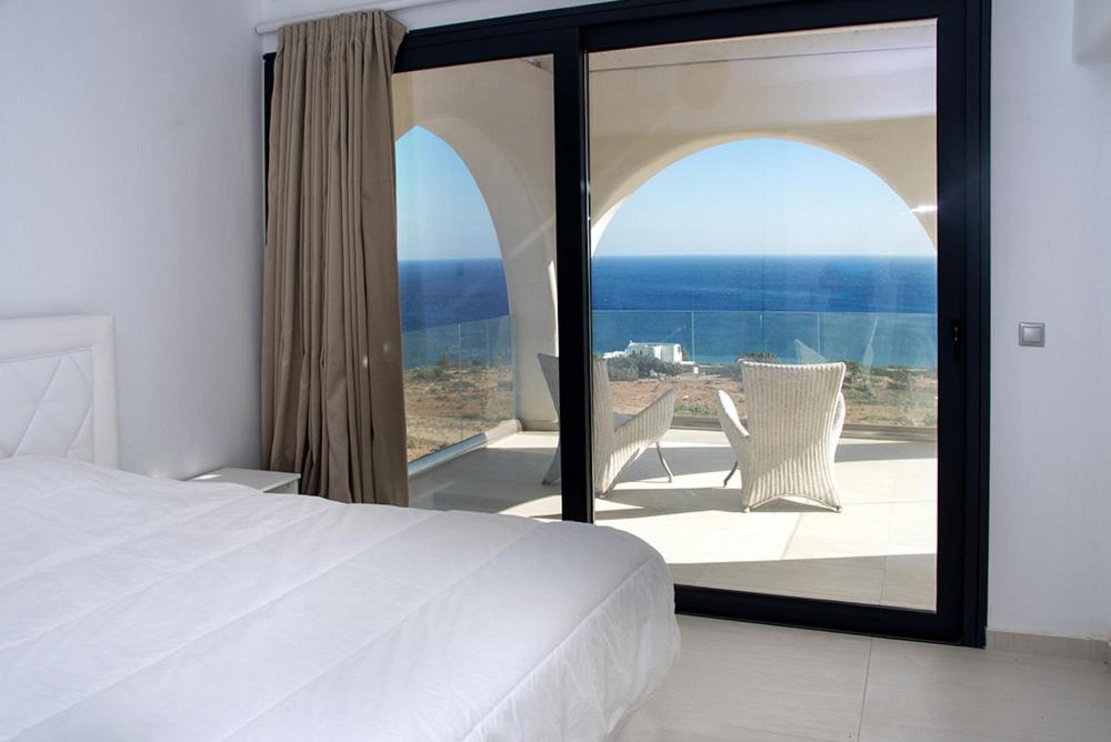 een slaapkamer met een bed en uitzicht op de oceaan bij EVILIA LUXURY VILLA in Amoopi
