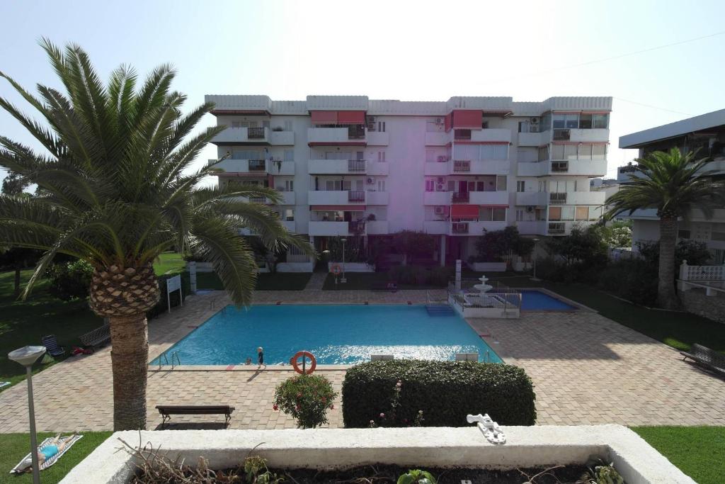 una piscina con una palmera y un edificio en VG1C, Gran apartamento en zona del Puerto, en Villajoyosa