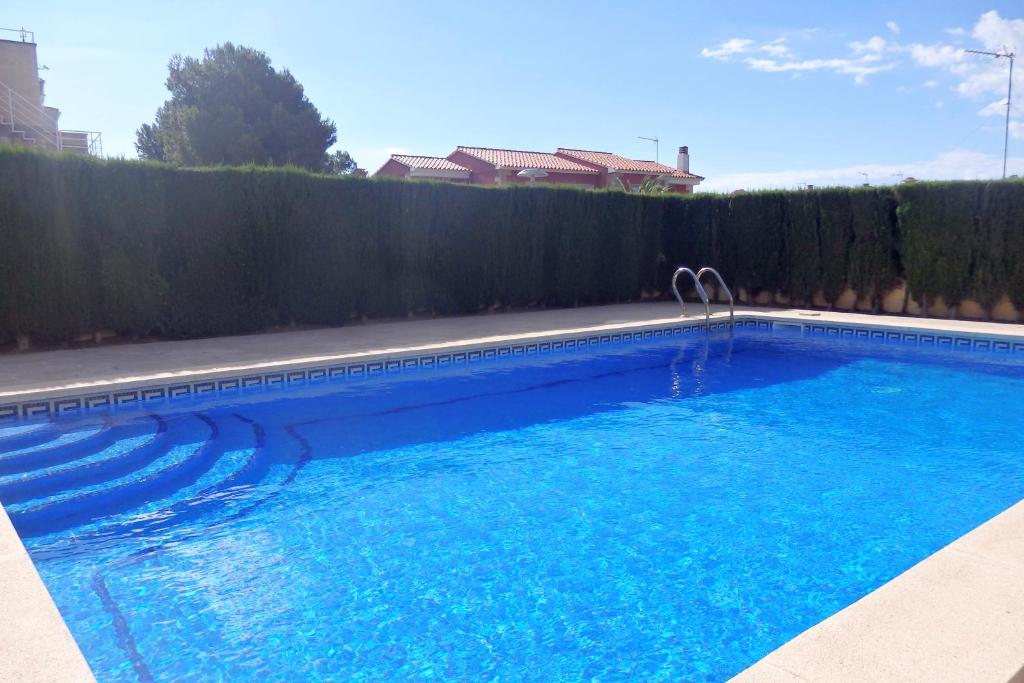 a swimming pool with blue water in front of a fence at MEDDAYS CHALET EUCALIPTUS 6 in Miami Platja