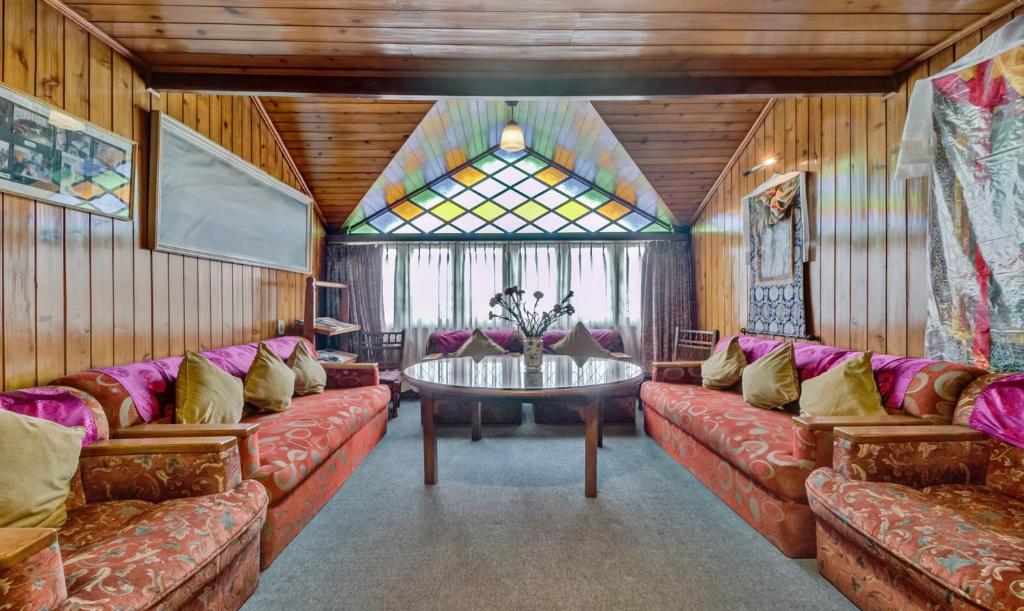 una sala de estar con sofás y una ventana de cristal. en Dekeling Hotel, en Darjeeling