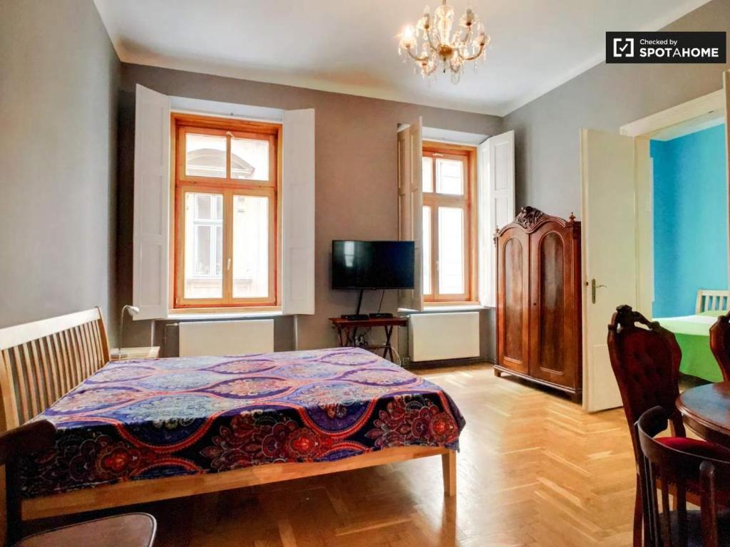 a bedroom with a bed and a television and windows at Market Square Apartment II. in Budapest