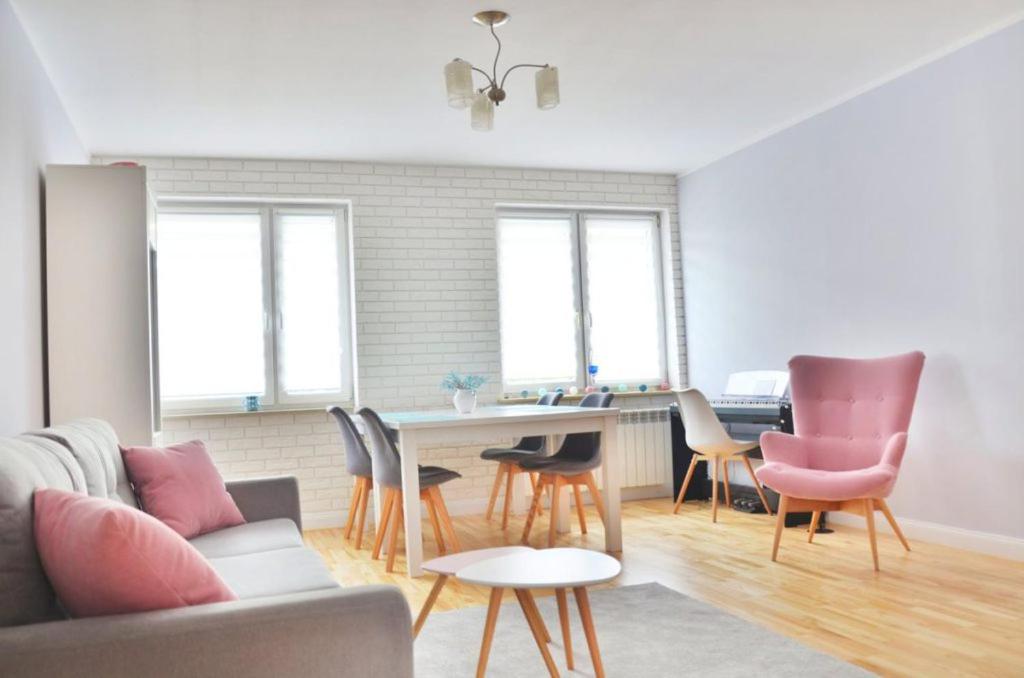 sala de estar con sofá, mesa y sillas en Apartament Promyczek, en Hajnówka