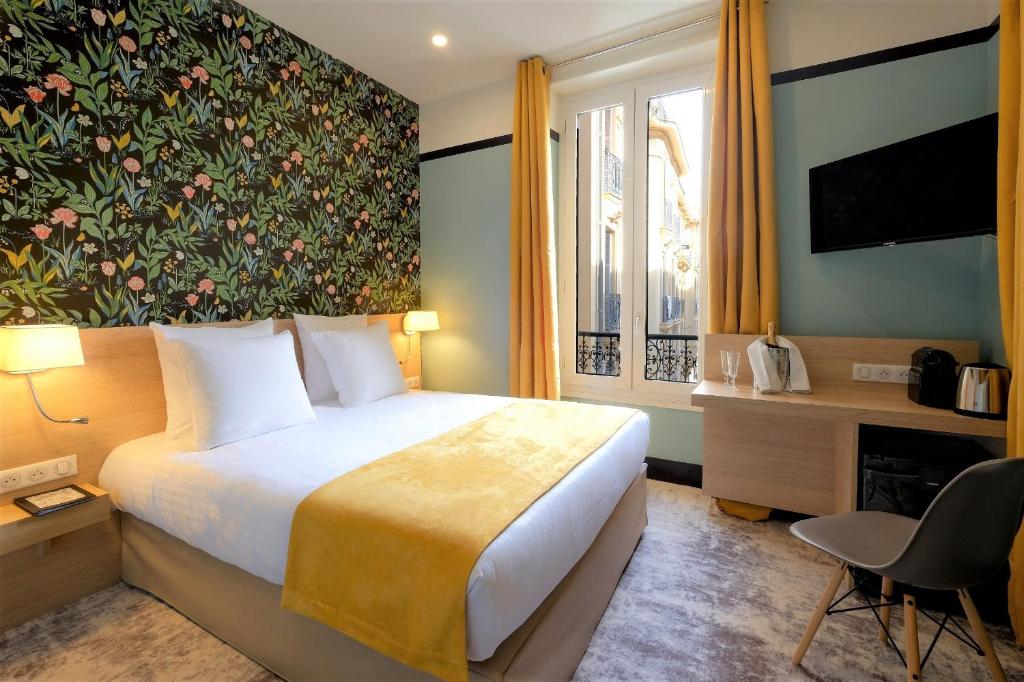 une chambre d'hôtel avec un lit et un mur fleuri dans l'établissement Hôtel de France, un hôtel AMMI, à Nice