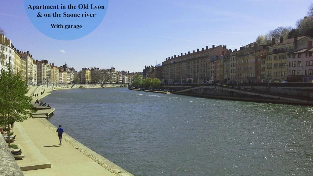 a person standing on a sidewalk next to a river at Apartment Pierre Scize Sur La Saône in Lyon