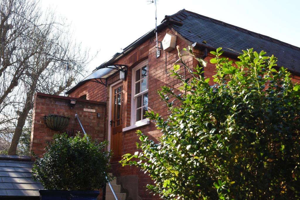 a red brick house with a window and bushes at Top Flat in Lincoln