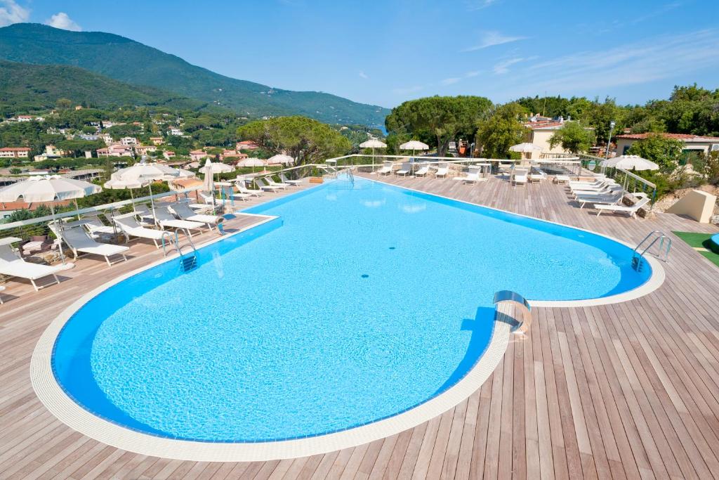 a pool at a resort with chairs and umbrellas at Hotel La Perla Del Golfo in Procchio