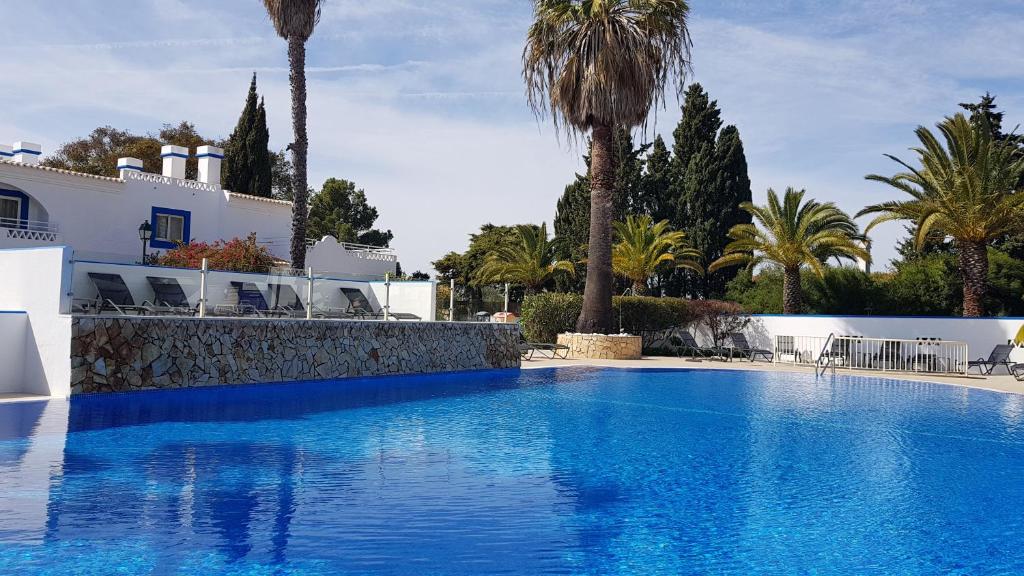 a large blue swimming pool with palm trees and buildings at Pestana Palm Gardens in Carvoeiro