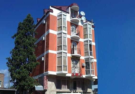 un edificio alto de color naranja y blanco con un árbol en Edemi, en Kutaisi