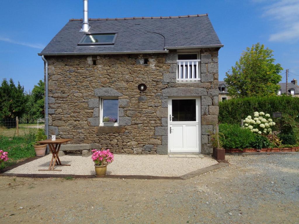 Ker Adsav o'naturel في Saint-Pierre-de-Plesguen: مبنى حجري صغير مع باب أبيض