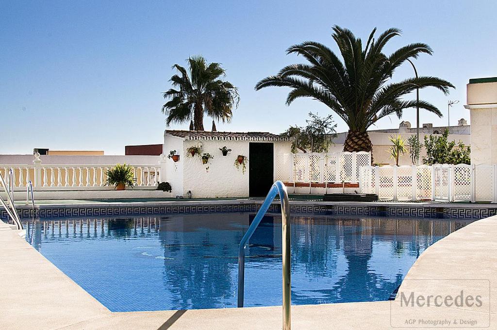 una piscina con vallas blancas y palmeras en Beautiful Apartment with Balcony and pool., en Torremolinos