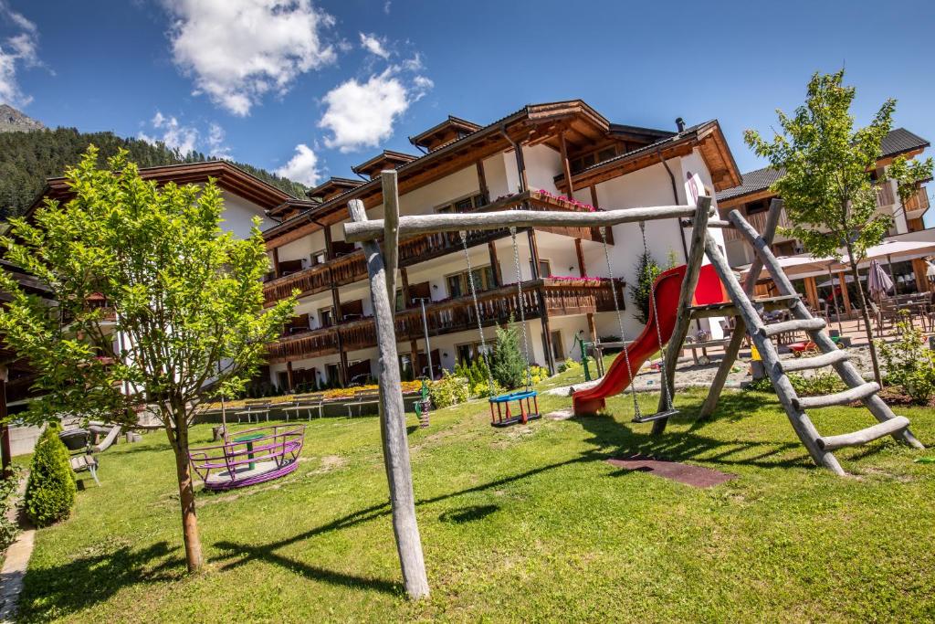 a playground in front of a building with a slide at Familienhotel Viktoria in Ultimo