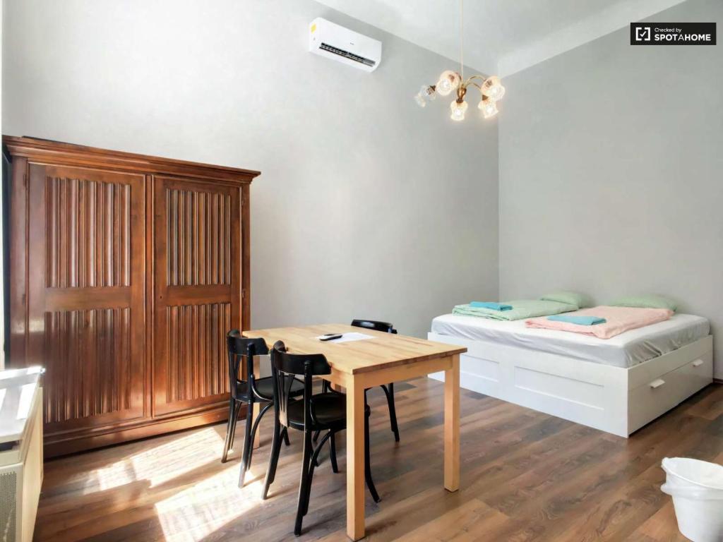 ブダペストにあるDob15 Small Apartmentのテーブル、ベッド、テーブル、椅子が備わる客室です。